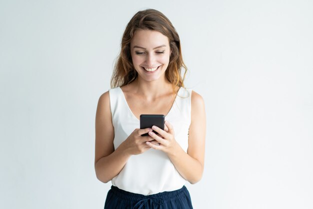 Lächelnde schöne frau, die auf smartphone simst Kostenlose Fotos