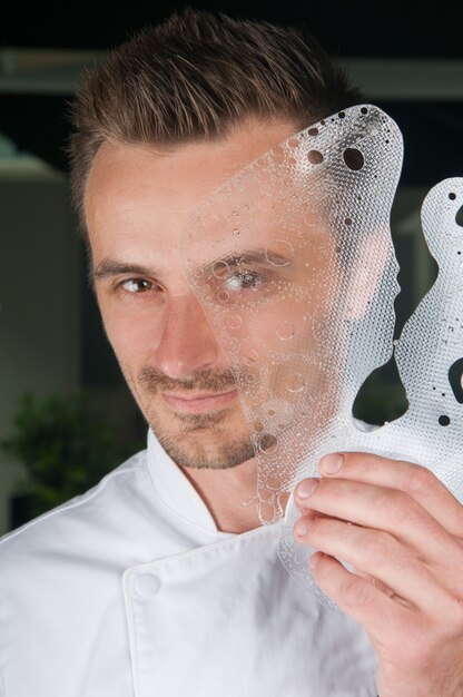 Lächelnder chef, der dekorative eisplatte vor seinem gesicht hält Kostenlose Fotos