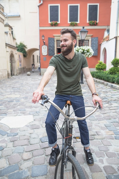 Lächelnder junger mann, der draußen auf fahrrad sitzt