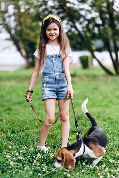 Lachelndes Kleines Madchen Das Mit Einem Hund Steht Und Die Kamera Betrachtet Premium Foto