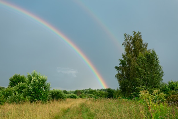 Premium Foto Landliche Szene Mit Natur Nach Dem Regen Mit Doppeltem Regenbogen Im Dunklen Himmel