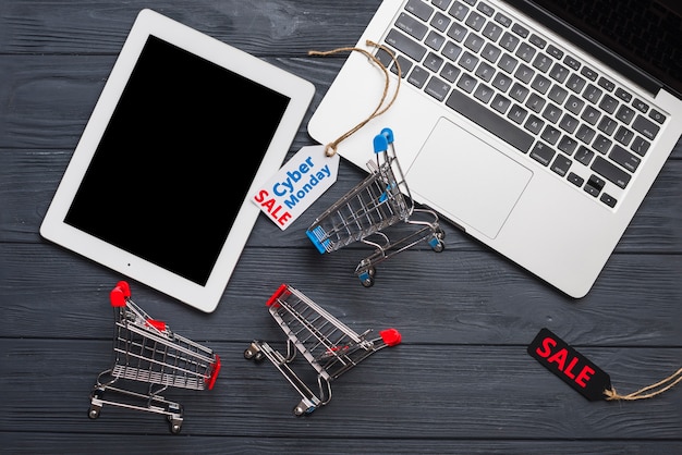 Laptop in der nähe von tags, tablet und supermarkt-wagen Kostenlose Fotos