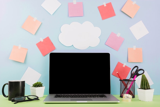 Laptop vor wand mit wolkenpapier und klebenden anmerkungen Kostenlose Fotos