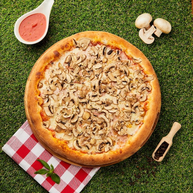 Leckere pizza mit pilzen und summen auf grünem gras | Premium-Foto