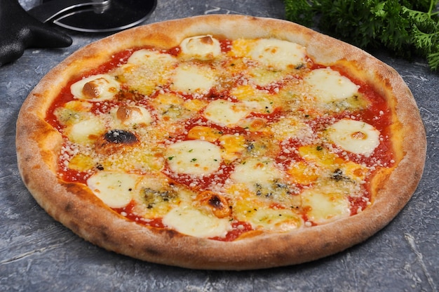 Leckere pizza vier käse auf einem grauen hintergrund mit grün verziert ...