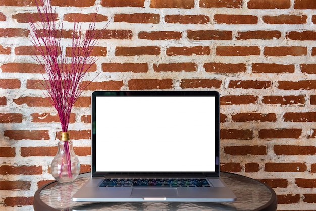 Leerer bildschirm der laptop-computers auf tabelle mit wand des roten backsteins Premium Fotos