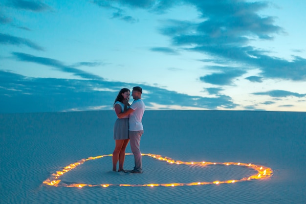 Liebespaar Romantische Umarmungen In Der Sandwuste Abend Romantische Atmosphare In Sand Brennen Kerzen In Form Von Herzen Premium Foto