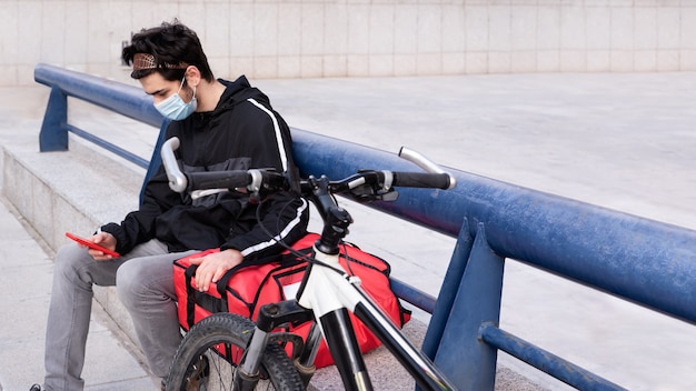 Lieferbote mit roter tasche und sitzendem fahrrad, mit