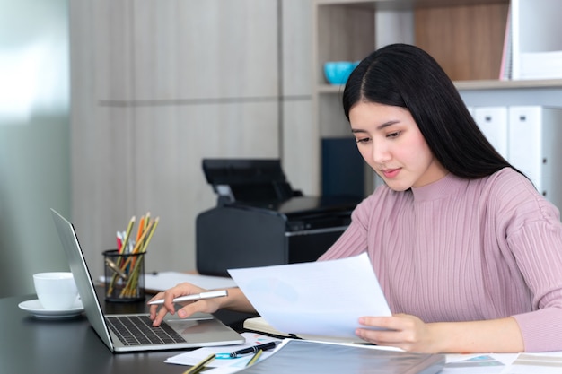 Lifestyle schöne asiatische business junge frau mit laptop-computer und smartphone am schreibtisch Kostenlose Fotos
