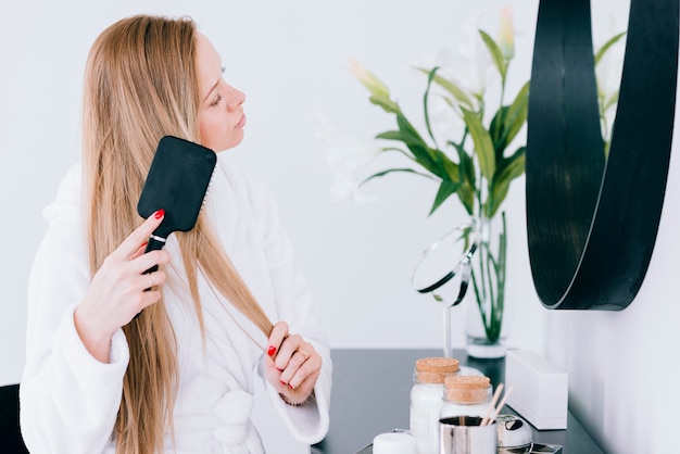 Mädchen, das ihr haar am badezimmer bürstet | Kostenlose Foto