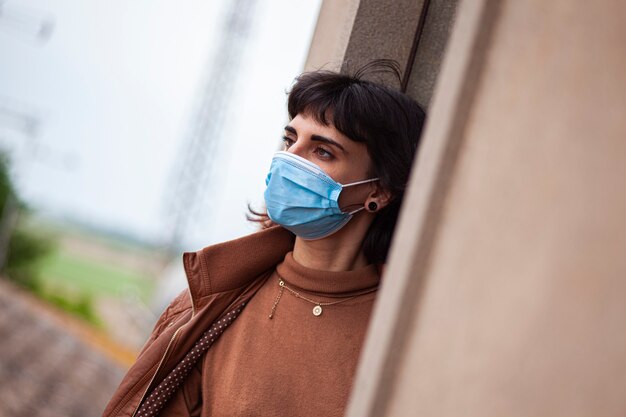 Mädchen mit medizinischer maske am fenster in ihrem haus