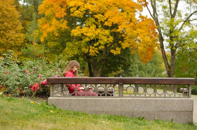 Mädchen sitzt auf bank und lesebuch, herbst. Premium Fotos
