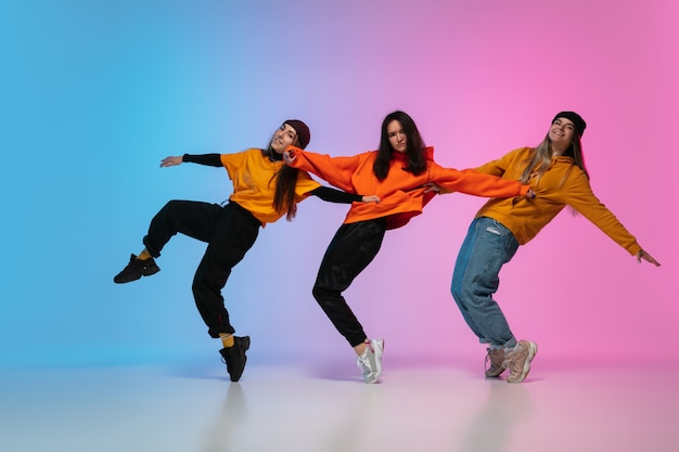 Mädchen tanzen hiphop in stilvollen kleidern auf gradient studio
