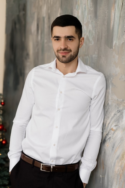 Mannliches Portrait Hubscher Brunettemann Im Weissen Hemd Und In Den Noblen Schwarzen Jeans Wirft Im Grauen Studio Auf Kostenlose Foto