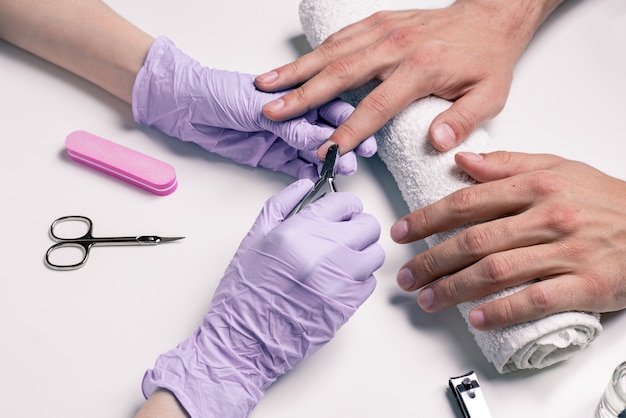 Premium Foto Manikure Fur Manner Kosmetikerin In Gummihandschuhen Schneidet Nagelhaut An Mannerhanden