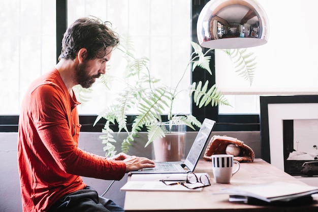 Mann arbeitet zu hause am laptop Kostenlose Foto