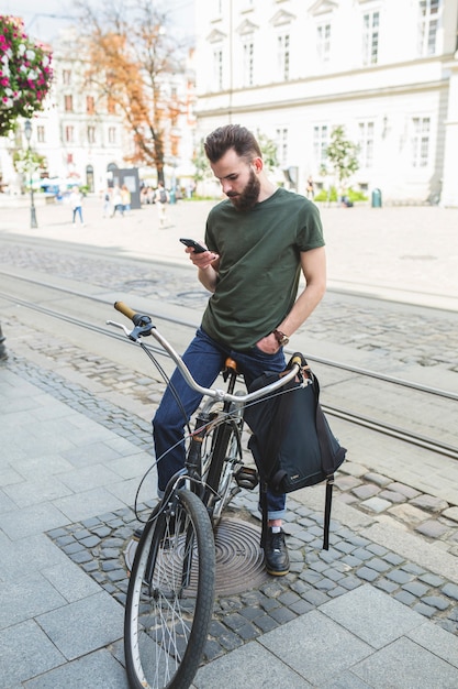 Mann, der auf fahrrad unter verwendung des handys sitzt