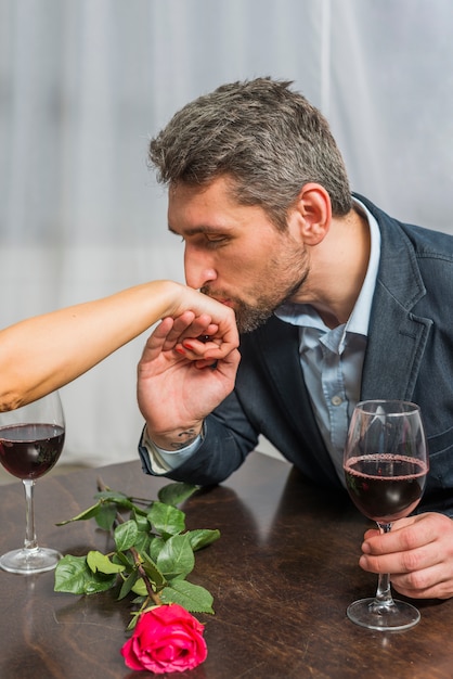 Mann mit glas der küssenden hand des weins der frau bei