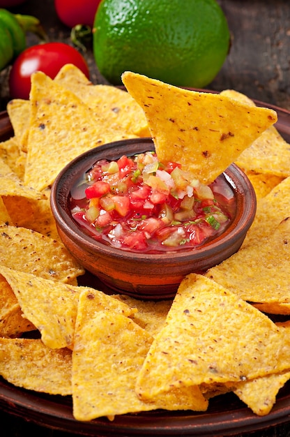 Mexikanische nacho-chips und salsa tauchen in eine schüssel auf holz ...