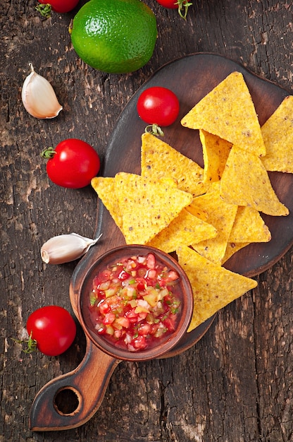 Mexikanische nacho-chips und salsa tauchen in eine schüssel ...