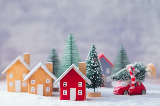 Miniaturholzhauser Und Kleines Rotes Auto Mit Tannenbaum Auf Dem Schnee Uber Unscharfer Weihnachtsdekoration Premium Foto