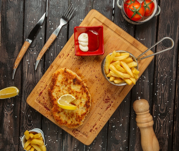 Mit zitrone garnierte hähnchenbrustpastetchen, serviert mit pommes frites, mayonnaise und ketchup Kostenlose Fotos