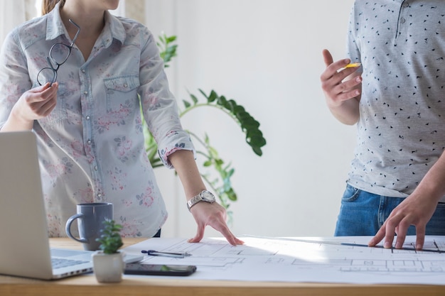 Mittelteil des mitarbeiters arbeitend an plan im büro Kostenlose Fotos