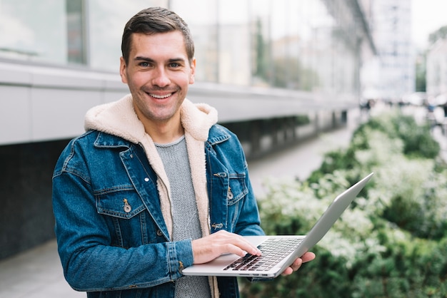 Moderner mann, der laptop in der städtischen umwelt verwendet Kostenlose Fotos