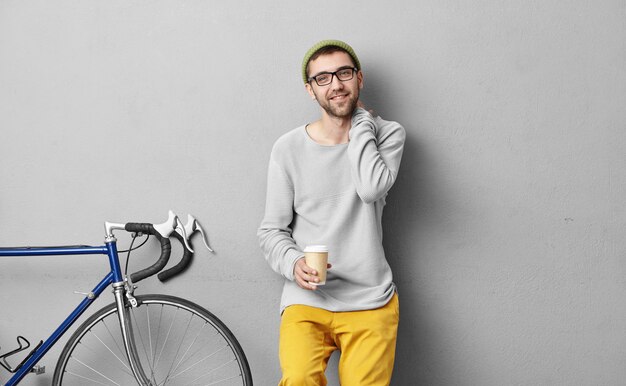 Modischer student, der nach dem unterricht mit dem fahrrad