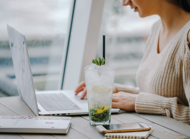 Mojito glas neben frau am notebook in der nähe des