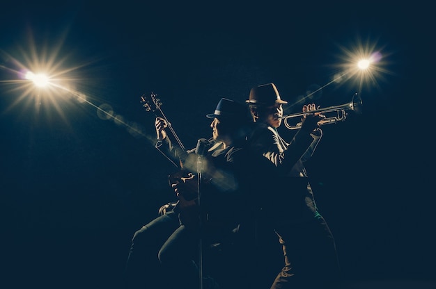 Musiker-duo-band, die eine trompete spielt und ein lied singt und die gitarre auf schwarzem hintergrund spielt wi Premium Fotos
