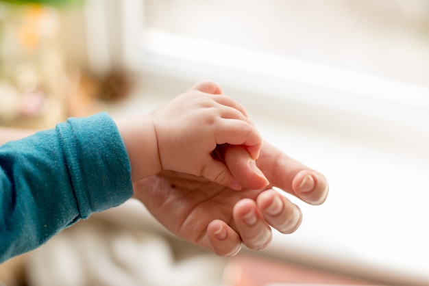 Mutter benutzt ihre hand, um die winzige hand ihres babys zu halten, damit er ihre liebe fühlt, warm und sicher. Premium Fotos