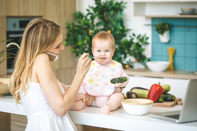 Mutter füttert ihr baby mit einem löffel. mutter, die