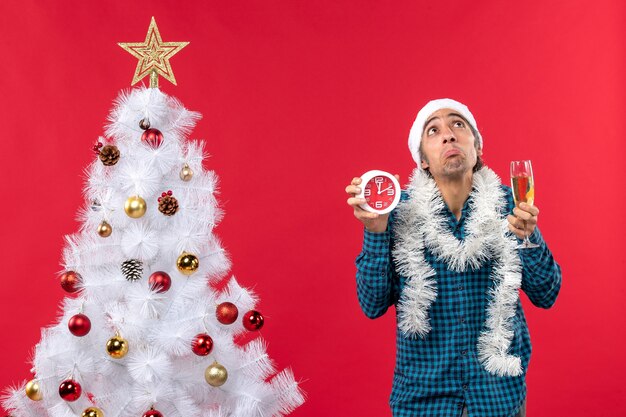 Nachdenklicher junger mann mit weihnachtsmannhut und hält