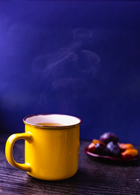 Nahaufnahme Gelbe Teetasse Auf Holzstander Dunkelblauer Hintergrund Fruchte Auf Einer Kleinen Keramikplatte Premium Foto