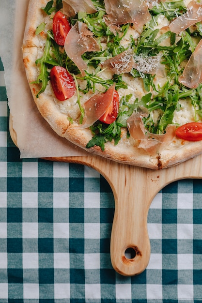 Neapolitanische pizza mit salami, rucola, tomaten besprüht mit käse auf ...