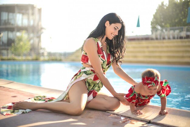 Nette mutter, die mit ihrer tochter nahe bei einem swimmingpool spielt Premium Fotos
