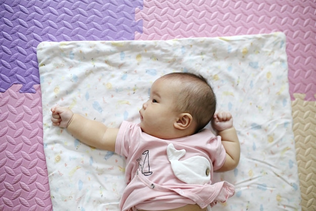 Nettes intelligentes asiatisches neugeborenes baby, das zu hause mit teddybärkaninchenspielzeug auf rosa weichem bett schläft. Premium Fotos