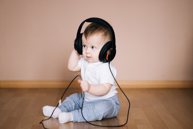 Nettes Junges Baby Das Zu Hause Auf Dem Boden Sitzt Und Mit Kopfhorern Spielt Die Musik Horen Premium Foto