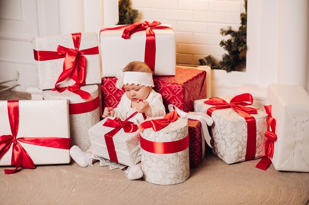 Nettes kind im weißen kleid, das unter weihnachtsbaum aufwirft. Premium Fotos