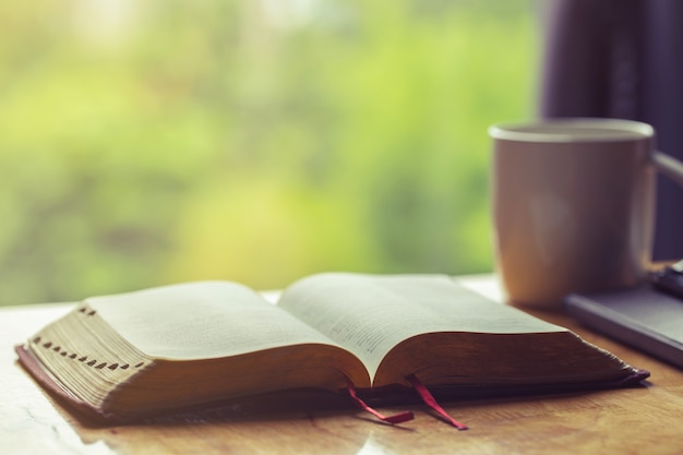 Öffnen sie bibel mit einem tasse kaffee für morgenandacht auf holztisch