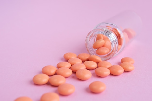 Orange tabletten von der glasflasche auf rosa Premium Fotos