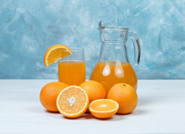 Orangensaft mit orangen in krug und glas | Kostenlose Foto