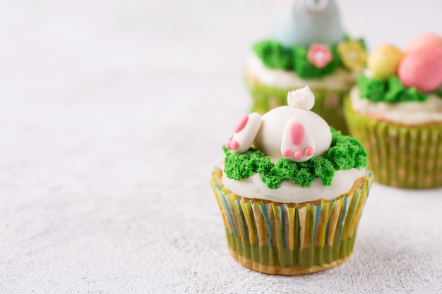 Ostern-kleine kuchen mit lustigem häschen und gras auf weißem hintergrund. ostern-feiertagskonzept Premium Fotos