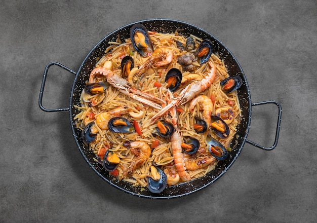 Pasta paella mit meeresfrüchten, spanische küche auf rustikalem tisch ...