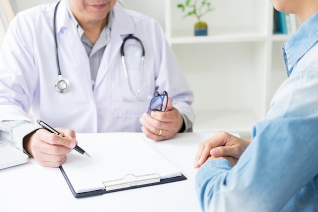 Patient, der aufmerksam auf einen männlichen arzt hört, der patientensymptome erklärt oder eine frage stellt, während sie in einer konsultation den papierkram besprechen Premium Fotos