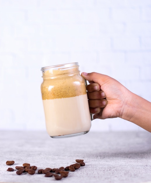 Person, die ein glas karamellsmoothie über kaffeebohnen