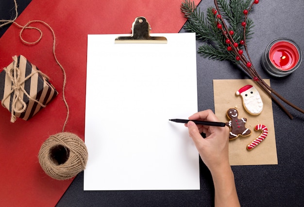 Person, die eine anmerkung mit geschmackvollen weihnachtsselbst gemachten plätzchen schreibt Premium Fotos