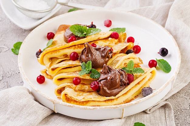 Pfannkuchen mit Beeren und Schokolade mit Minzblatt verziert