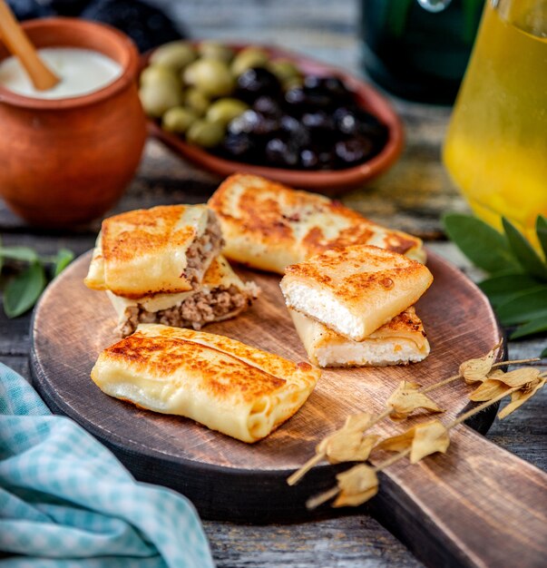 Pfannkuchen mit fleisch und hüttenkäse auf einem hölzernen brett ...